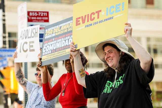 Demonstrators holding 'Evict ICE from 250 Delaware' signs