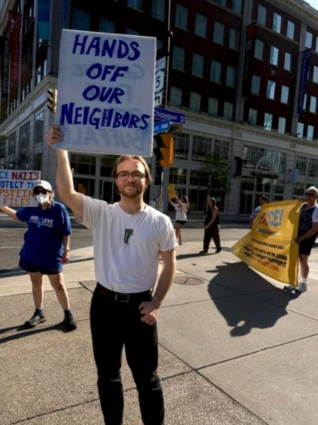 Demonstrator holding a 'Hands off our neighbors' sign